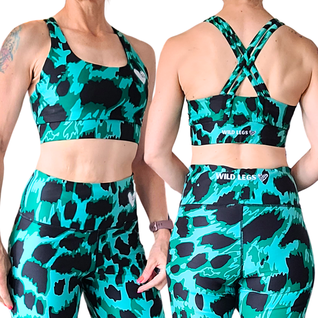 Emerald green and black patterned sports bra and leggings set worn by a model on a white background.