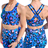 Woman wearing front zip sports bra in blue, pink, purple and black leopard print, front and racer back showing Wild Legs logo