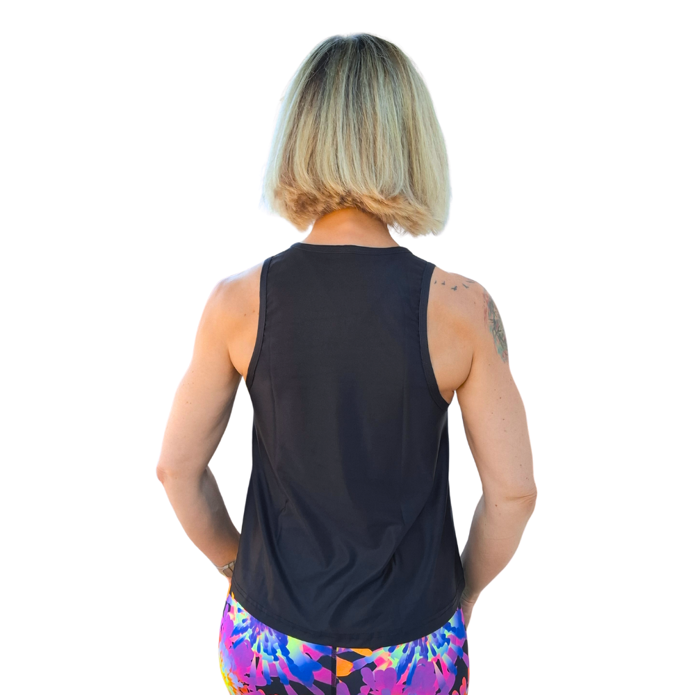 Person wearing a black sleeveless top and colorful leggings on a white background