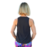 Person wearing a black sleeveless top and colorful leggings on a white background