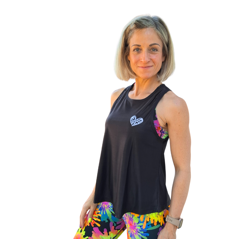 Woman wearing a black sleeveless top with a logo and colorful leggings on a white background