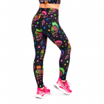 A model from the waist down wearing high-waisted leggings with a vibrant neon multicolour sugar skull and paisley print on a black background, paired with pink trainers, against a plain white background.
