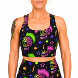 A woman wearing a matching black activewear set with a vibrant neon sugar skull and star pattern, shown against a plain white background.