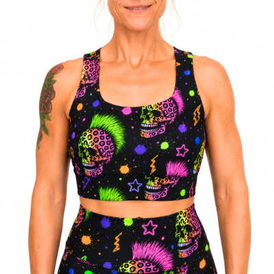 A woman wearing a matching black activewear set with a vibrant neon sugar skull and star pattern, shown against a plain white background.