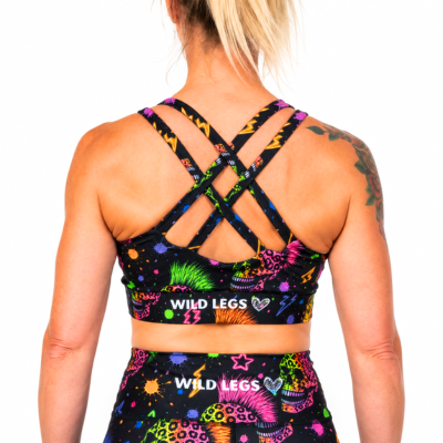 Rear view of a woman wearing a black sports bra and matching high-waisted leggings set by Wild Legs, featuring a vibrant multicolor neon pattern and crisscross back straps.