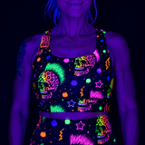 A person wearing a black UV-reactive sports bra and matching bottoms with neon multicolor sugar skull and star patterns, shown under blacklight against a dark background.