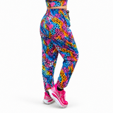 A person shown from the back wearing bright multicolour patterned jogger-style leggings and matching athletic top, with pink trainers, against a plain white studio background.