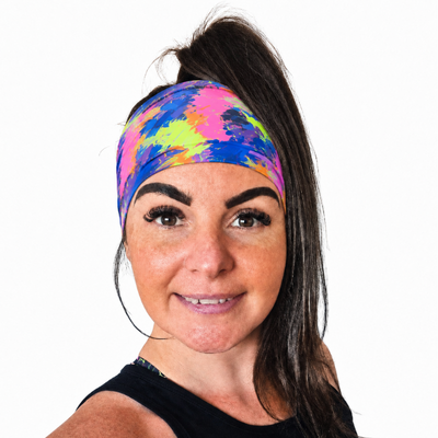 Woman wearing a colourful paint splash design fitness headband on a white background