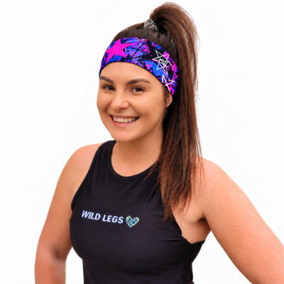 Woman wearing a sweat head band with pink and blue star pattern in a black fitness vest that has a Wild Legs Logo on a White Background