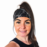 Woman wearing a black with white lightening strikes headband on a white background