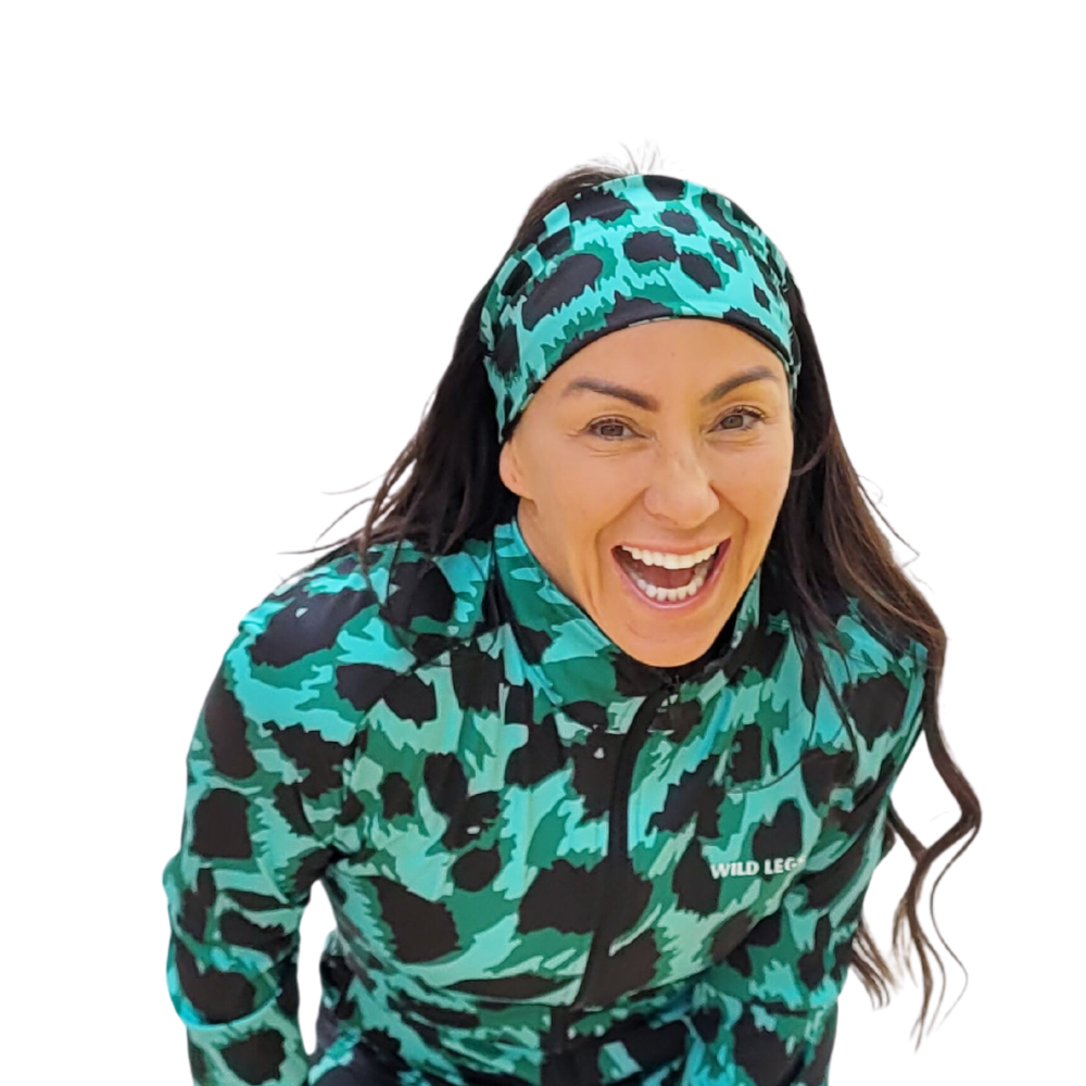 Person wearing a green and black animal print patterned outfit with a matching headband on a white background