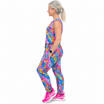 A woman in profile wearing a sleeveless athletic jumpsuit with a bright multicolour animal print, paired with pink trainers, against a plain white background.