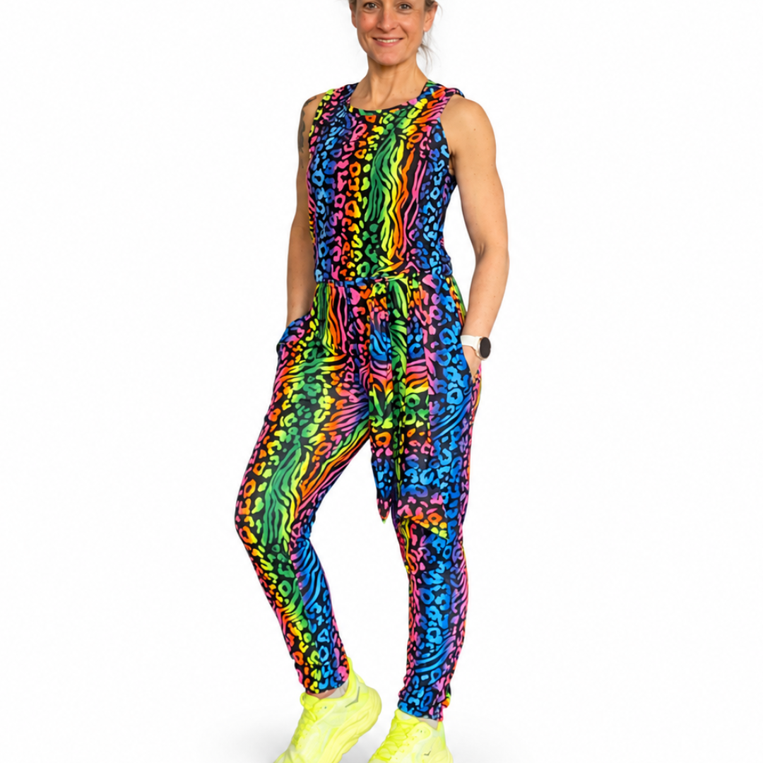 Person wearing a colorful sleeveless animal print jumpsuit with neon shoes on a white background