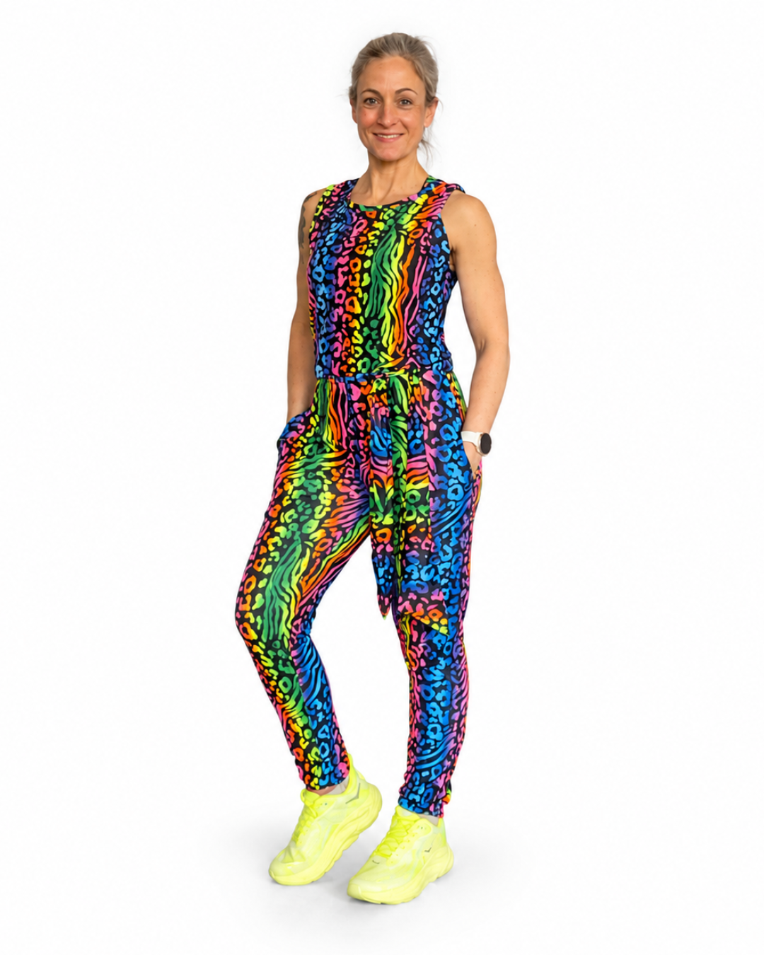 Person wearing a colorful sleeveless animal print jumpsuit with neon shoes on a white background