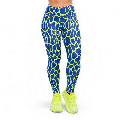 A person from the waist down wearing high-waisted leggings with a blue and neon yellow giraffe-like pattern, paired with neon yellow trainers, on a plain white background.