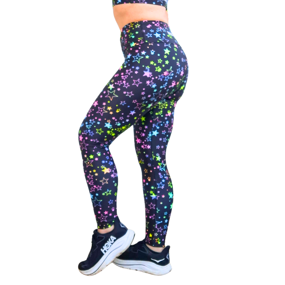 Person wearing black leggings with colorful star patterns on a white background