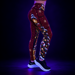 Red Christmas Fitness Leggings shown under UV light with Candy Canes, Christmas shop fronts, snow flakes, lanterns and snowy tress with black shoes on a white background