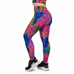 A person wearing bright neon rainbow leopard-print leggings and a matching crop top, shown from the waist down against a plain white background.