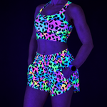 Person wearing a colorful UV reactive outfit with a leopard print pattern on a black background