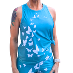 Person wearing a blue tank top with white butterfly patterns on a white background
