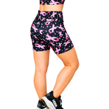 Black shorts with pink ribbon pattern worn by a person on a white background