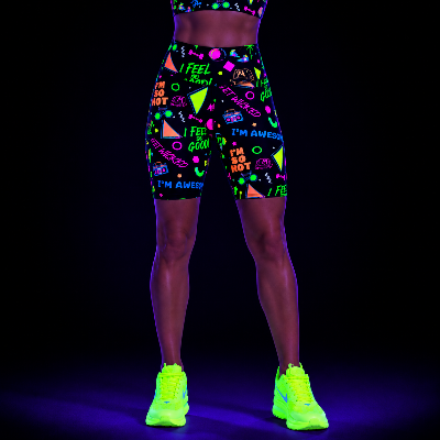Person wearing UV-reactive shorts and shoes on a black background with 90s retro slogan pattern
