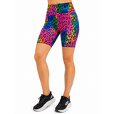 A model wearing high-waisted athletic shorts with a vibrant rainbow neon leopard print, paired with black trainers, shown against a plain white background.