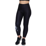 Black high-waisted athletic leggings with a white graphic print on the lower left leg, shown on a model from the waist down wearing black trainers against a white background.