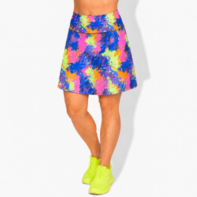 A model's lower body wearing a vibrant, multicoloured paint splash  print skort with neon yellow-green trainers, set against a plain white studio background.
