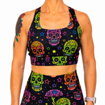 A woman wearing a matching black activewear set with a vibrant, multicolored sugar skull and star print, shown against a plain white background.