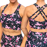 Black sports bra and shorts with pink ribbon pattern worn by a person.