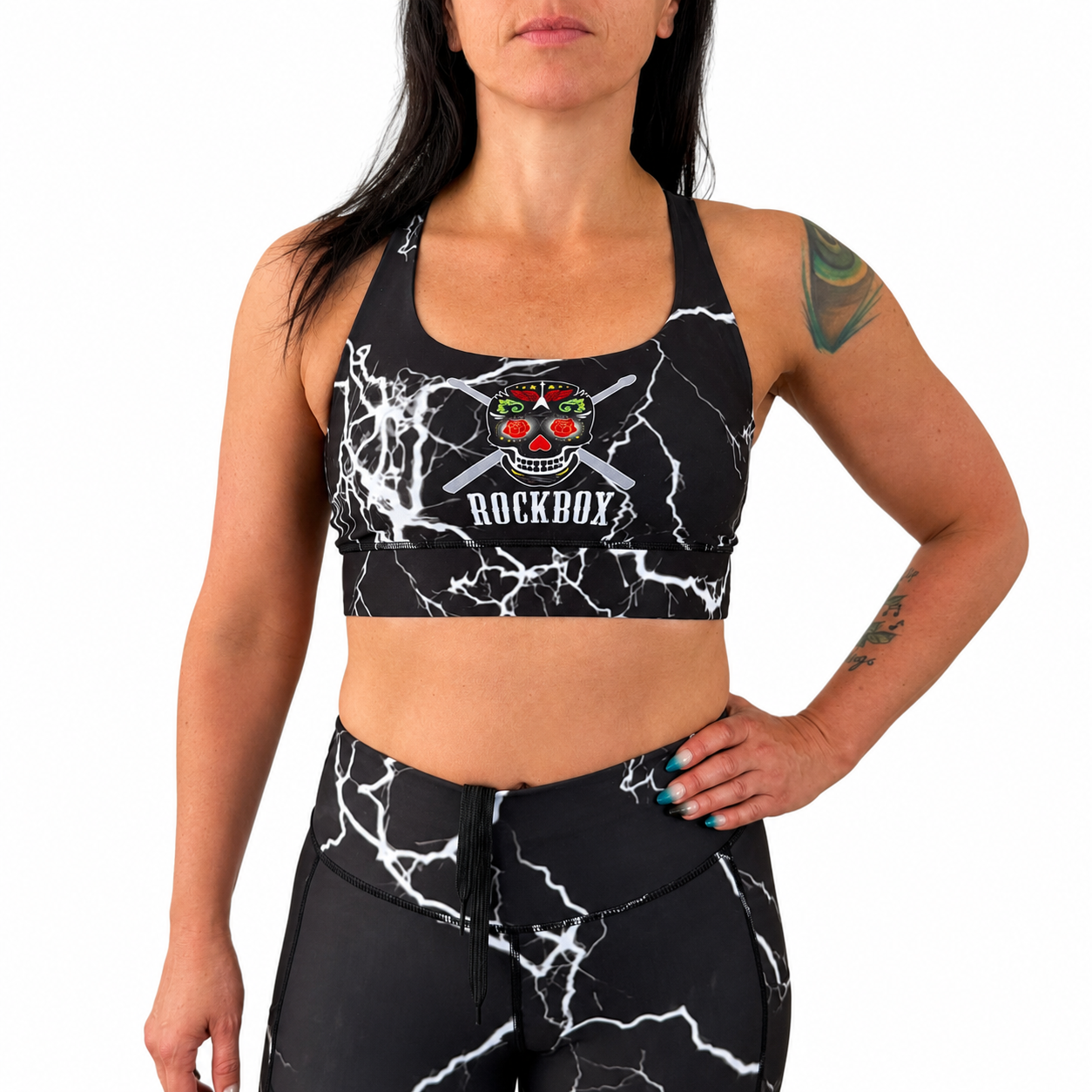 Woman wearing a black sports bra and leggings with a graphic design on a white background