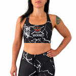 Woman wearing a black sports bra and leggings with a graphic design on a white background