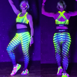 Person wearing a UV reactive outfit with glowing patterns on a dark background