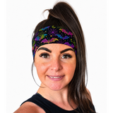 Women with dark hair and a high ponytail wearing a neon rainbow Halloween design headband on a white background