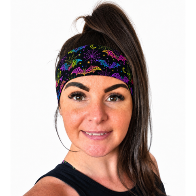 Women with dark hair and a high ponytail wearing a neon rainbow Halloween design headband on a white background