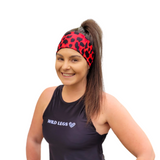 Woman wearing a black tank top with 'Wild Legs' text and a red leopard print headband on a white background