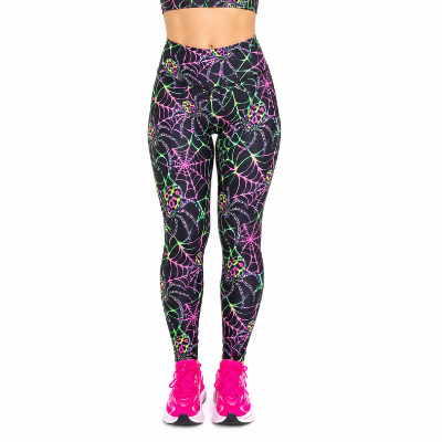 A person from the waist down wearing high-waisted leggings with a neon pink, green, and yellow spiderweb and flower pattern on a black background, paired with bright pink running shoes, against a plain white background.
