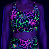 A black two-piece activewear set featuring a vibrant neon UV-reactive spiderweb and spider print, shown on a model under blacklight.