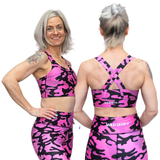 Woman wearing pink and black camouflage sports bra and leggings with 'Wild Legs' branding.
