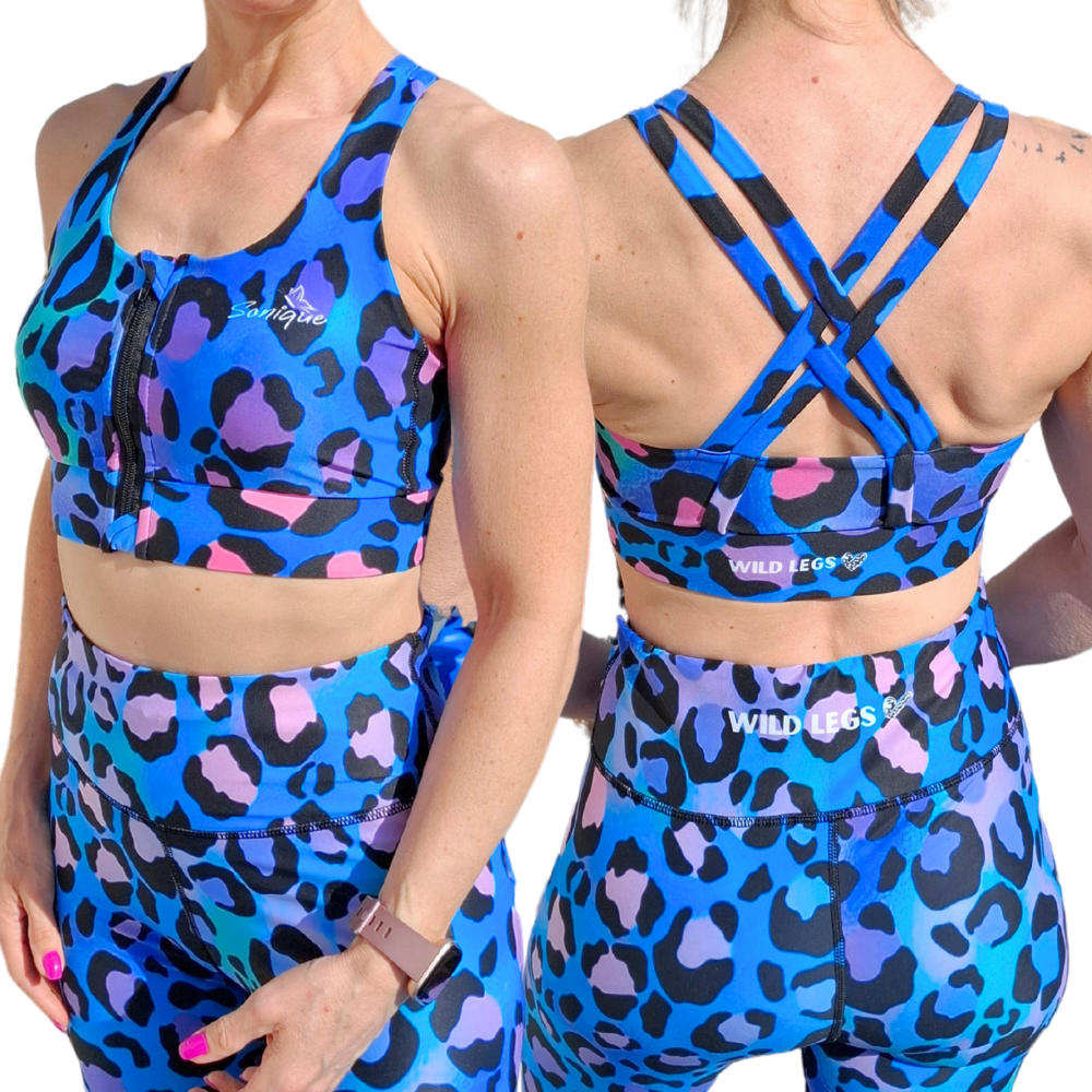Woman wearing front zip sports bra in blue, pink, purple and black leopard print, front and racer back showing Wild Legs logo