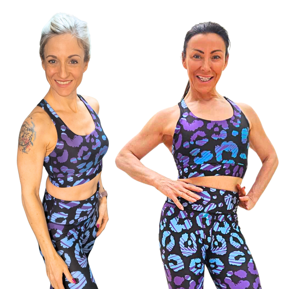 Two women wearing matching purple and blue patterned sports bras and leggings on a white background